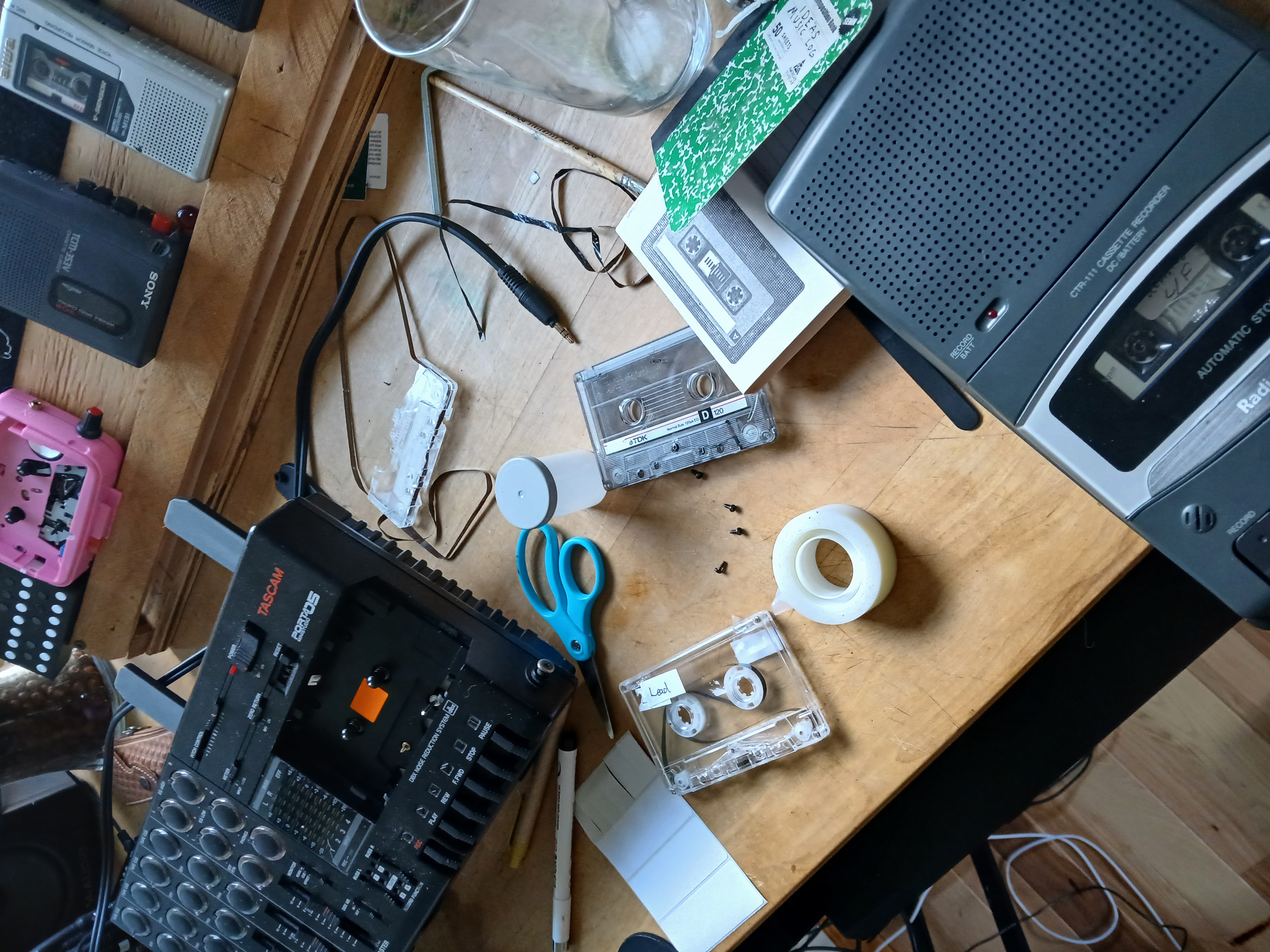 A picture of a Tascam cassette deck with a tape loop. The tape loop is made from a piece of clear plastic tape, and is shown in the process of being recorded. The cassette deck is connected to a mixer and a laptop.